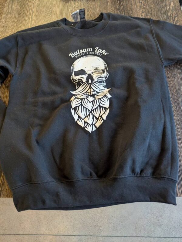 Black Skull Hop Beard Tee, showcasing a skull with a beard design and the text "Baksan Lake Project Oberstdorf," displayed on a wooden surface.