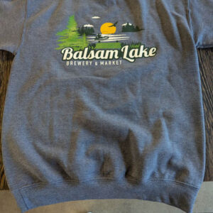 Navy crew neck sweatshirt with "Balsam Lake Brewery & Market" written on it, featuring a fishing scene with trees, water, and sun. Sneakers visible at the bottom of the image.