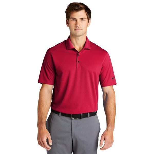 A person wearing a Nike Dri-FIT Micro golf shirt in red and gray pants stands against a plain white background.